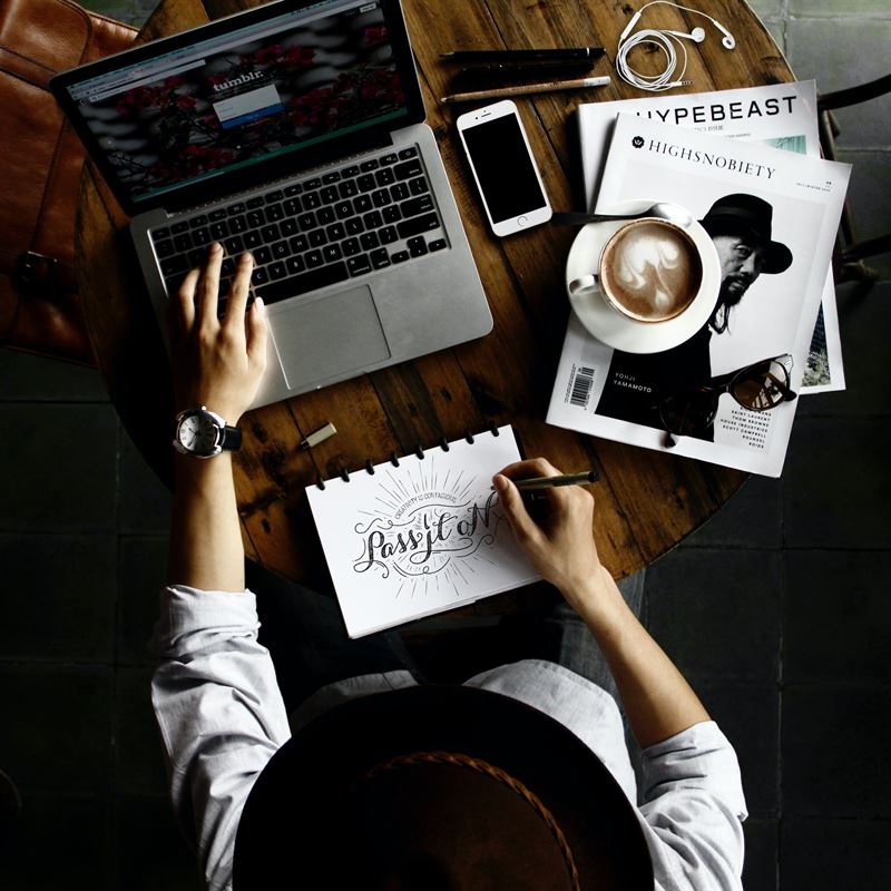 Person Sitting Facing Laptop Computer with Sketch Pad